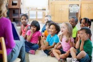 Daycare teacher reading to a group of preschool students