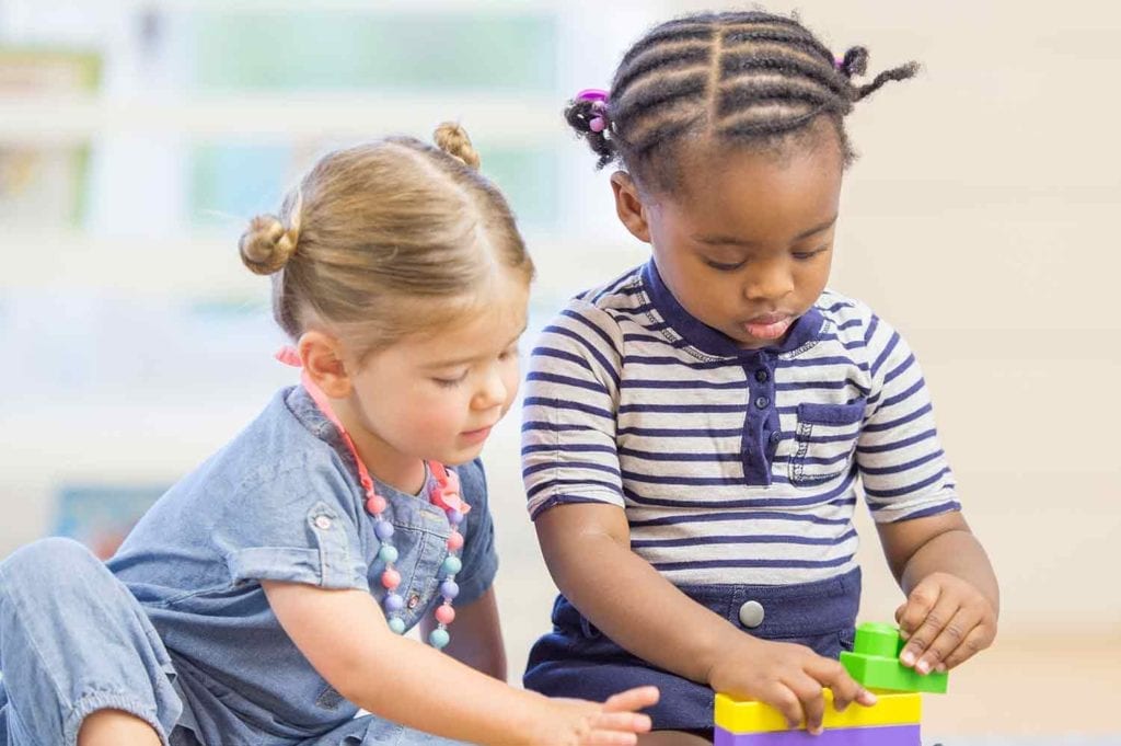 Toddler girls playing in daycare while stacking blocks