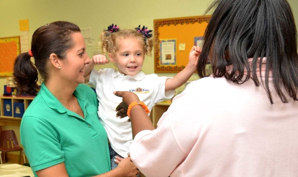 Teacher, parent and toddler in childcare classroom