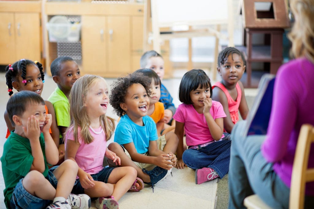 Daycare teacher reading to a group of preschool students