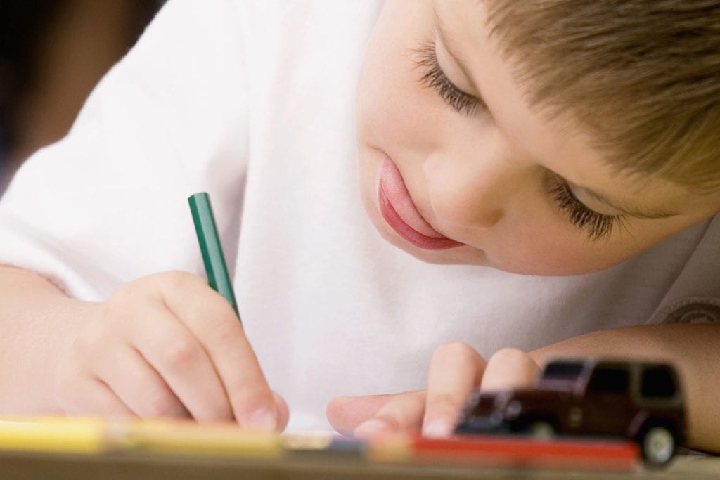 Boy concentrating and writing at daycare